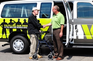 Two men shaking hands in front of a VA Portland Health Care System van
